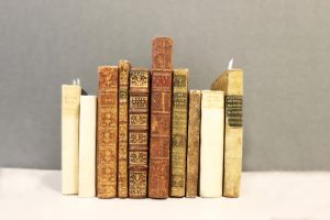 Antique books lined up against a gray backdrop.