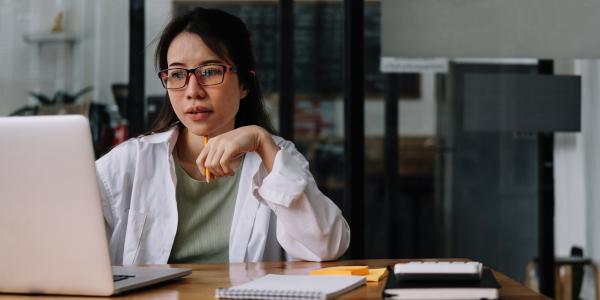 Woman in a lab coat looking at a computer screen