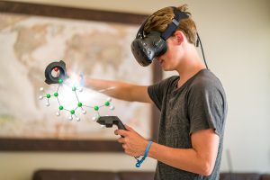 A teenage student wearing a virtual reality headset to study.