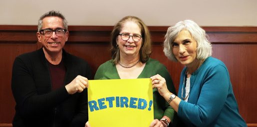 Smiling librarians hold a sign with the word Retired!