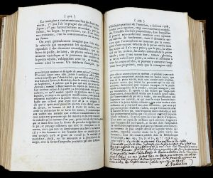 Open book laid flat, featuring printed text and a handwritten footnote in French.