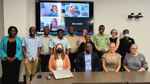 Both Pittsburgh and Zimbabwe based professionals gathered at a table with some appearing on a screen as webinar participants.