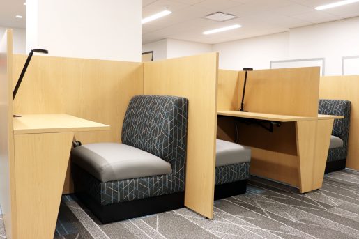 Three wood study carrels each with a padded both-style seat and reading light.