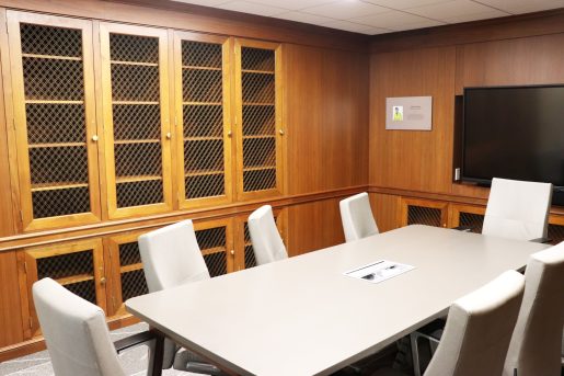 A wood-paneled room with built-in bookcases, with a long conference table in the center of the room.